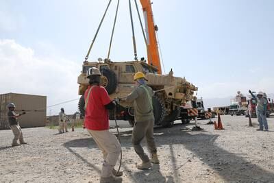 Civilian contractors prepare to load a Mine Resistant Ambush Protected vehicle on to a flatbed trailer during the retrograde cargo operation on Bagram Air Field, Afghanistan, July 12, 2020.