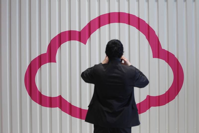 A person photographs a symbol of a cloud at the Deutsche Telekom stand the day before the CeBIT 2012 technology trade fair officially opens in Hanover, Germany.