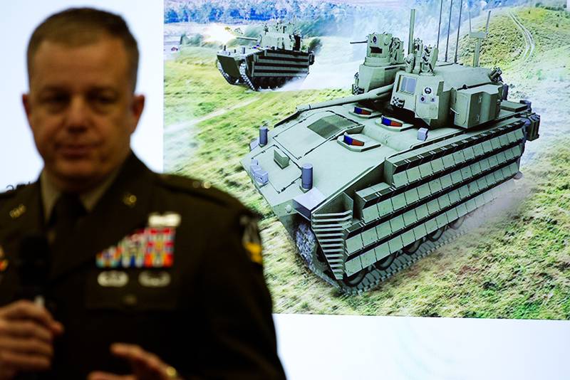 A rendering of the Optionally Manned Fighting Vehicle, or OMFV, is seen behind Brig. Gen. Geoffrey Norman, an official with the Next Generation Combat Vehicles Cross-Functional Team.