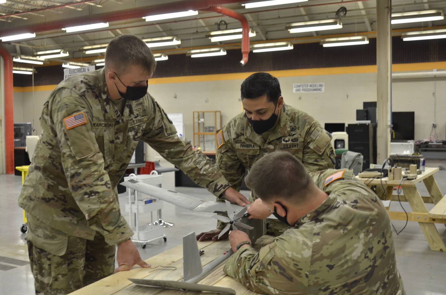 Staff Sgt. Charles Pugh secures a 3D-printed propeller system onto an RQ-11B Raven drone for a test run in August 2021 at the EagleWerx Applied Tactical Innovation Center. Also pictured are Sgt. Scott Karczewski,, and Chief Warrant Officer 2 Ron Rivera.
