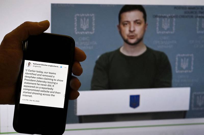 This illustration photo taken in January shows a phone screen with a statement from the head of security policy at META with a fake video of Ukrainian President Volodymyr Zelenskyy calling on his soldiers to lay down their weapons shown in the background.