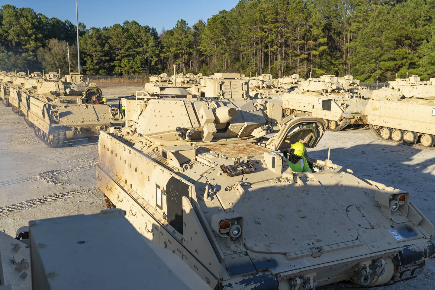 In this image provided by U.S. Transportation Command, a stevedore sits in a Bradley Fighting Vehicle before loading it onto the ARC Wallenius Wilhemsen Jan. 25, 2023, at the Transportation Core Dock in North Charleston, S.C.