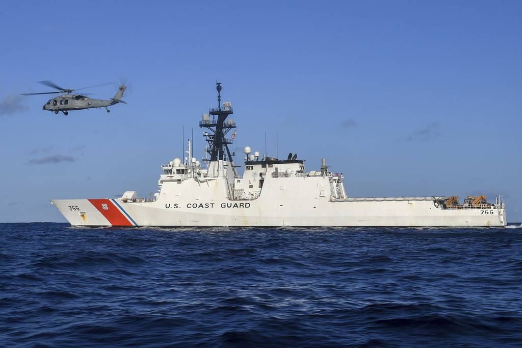 In this Aug. 25, 2020, photo provided by the U.S. Navy, an MH-60S Sea Hawk helicopter hovers next to the Legend-class cutter USCGC Munro in the Pacific Ocean.