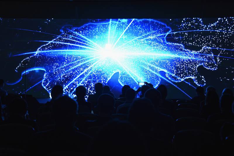 People are silhouetted by a massive digital display at a communications and cybersecurity conference in Switzerland in November 2018.