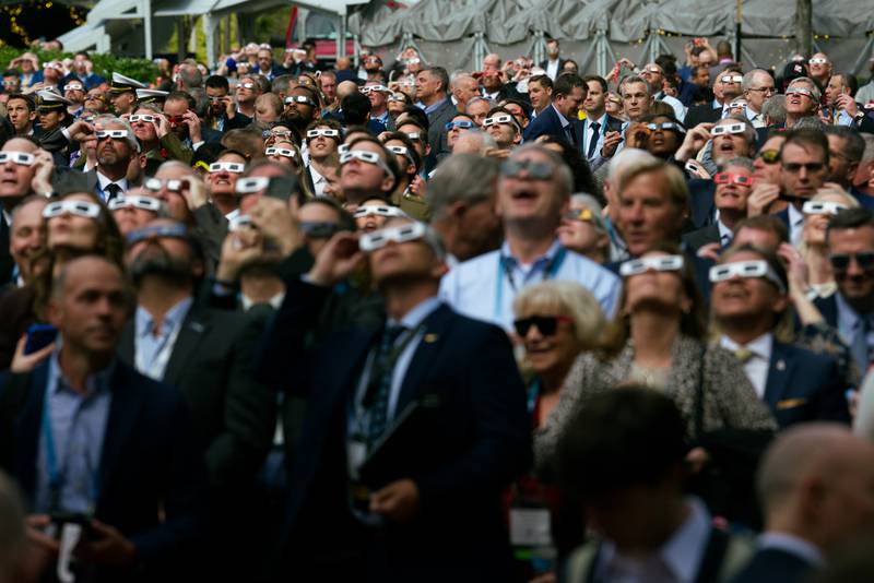 Sea-Air-Space attendees step out of the naval conference in National Harbor, Maryland, to observe the solar eclipse April 8, 2024.