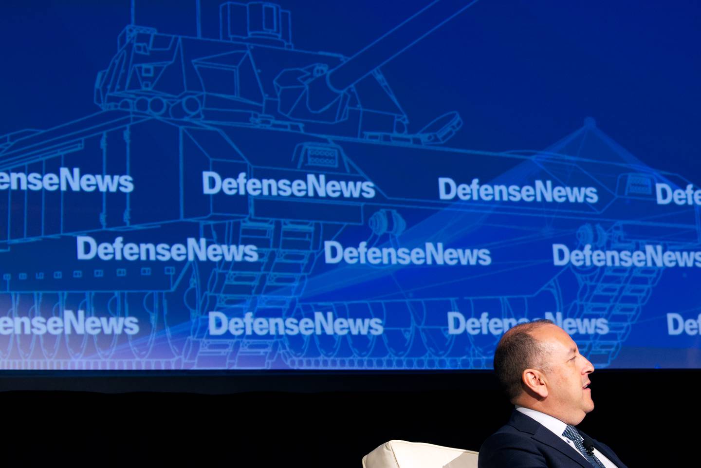 Undersecretary of the Army Gabe Camarillo is seen speaking Sept. 7 at the Defense News Conference. Behind him, an illustration of a tank.